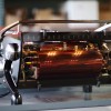 This image is a back panel view of the Slayer Espresso custom machine with a smoked glass structure, plated boiler, with side panels and x-legs powder coated black, groups at traditional height with manual dosing controls.